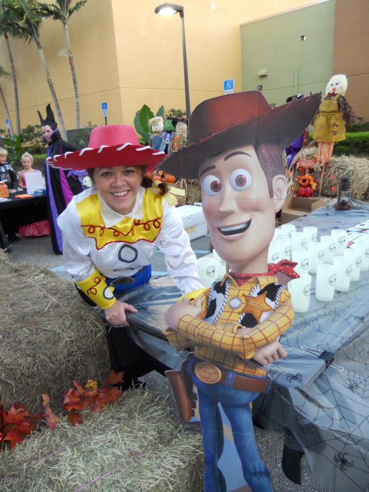 Woman dressed as Jessie from Toy Story takes photo with cardboard cutout of Woody